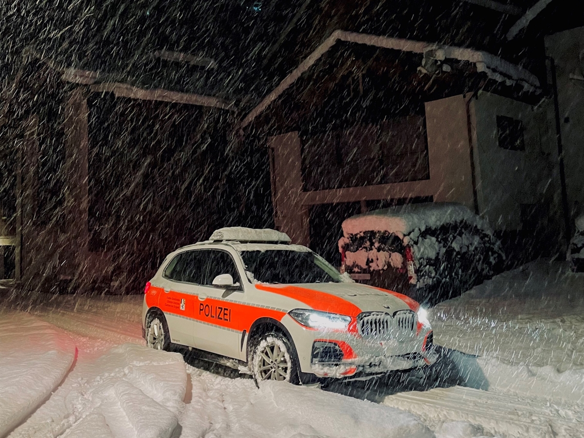 Ein Polizeiauto auf einer verschneiten Strasse in einem Bündner Dorf. 