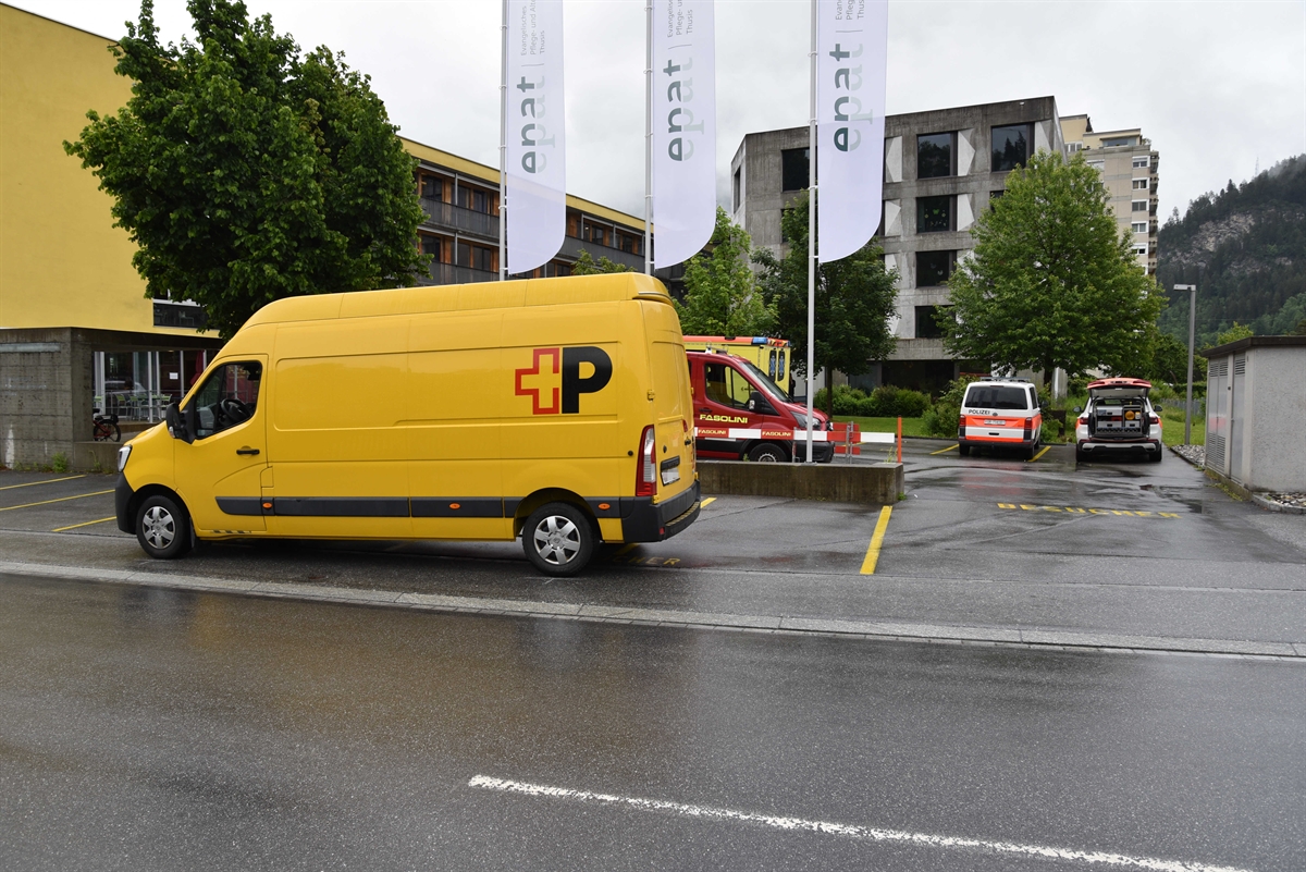 Strassenverlauf der Compognastrasse in Thusis im Bereich der Unfallstelle. Im Vordergrund ist der beteiligte Lieferwagen zu erkennen. Im Hintergrund sind noch zwei Polizeifahrzeug zu erkennen.