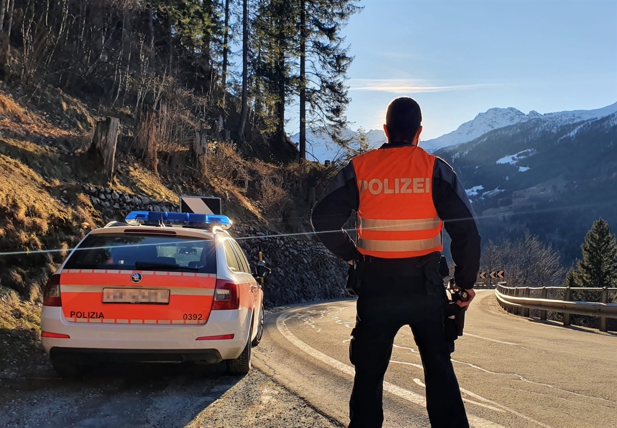 Polizeibeamter neben Polizeiauto mit Blick in Richtung Tal