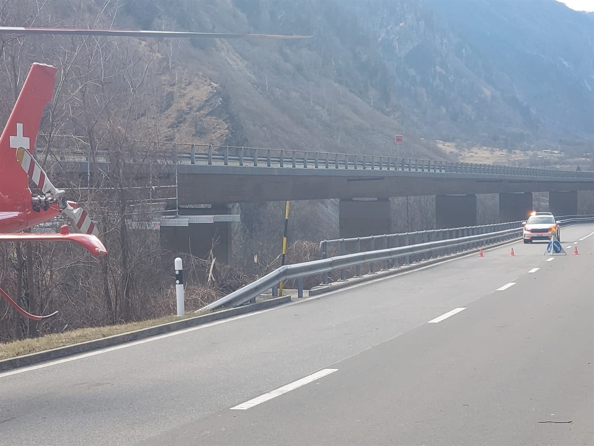 Die Hauptstrasse H13 neben der Autostrassenbrücke der A13. Am linken Bildrand der Heckrotor des Rega-Helikopters. Rechts ein Patrouillenauto der Kapo. Unter der Brücke der A13 das Gerüst im Aufbau.