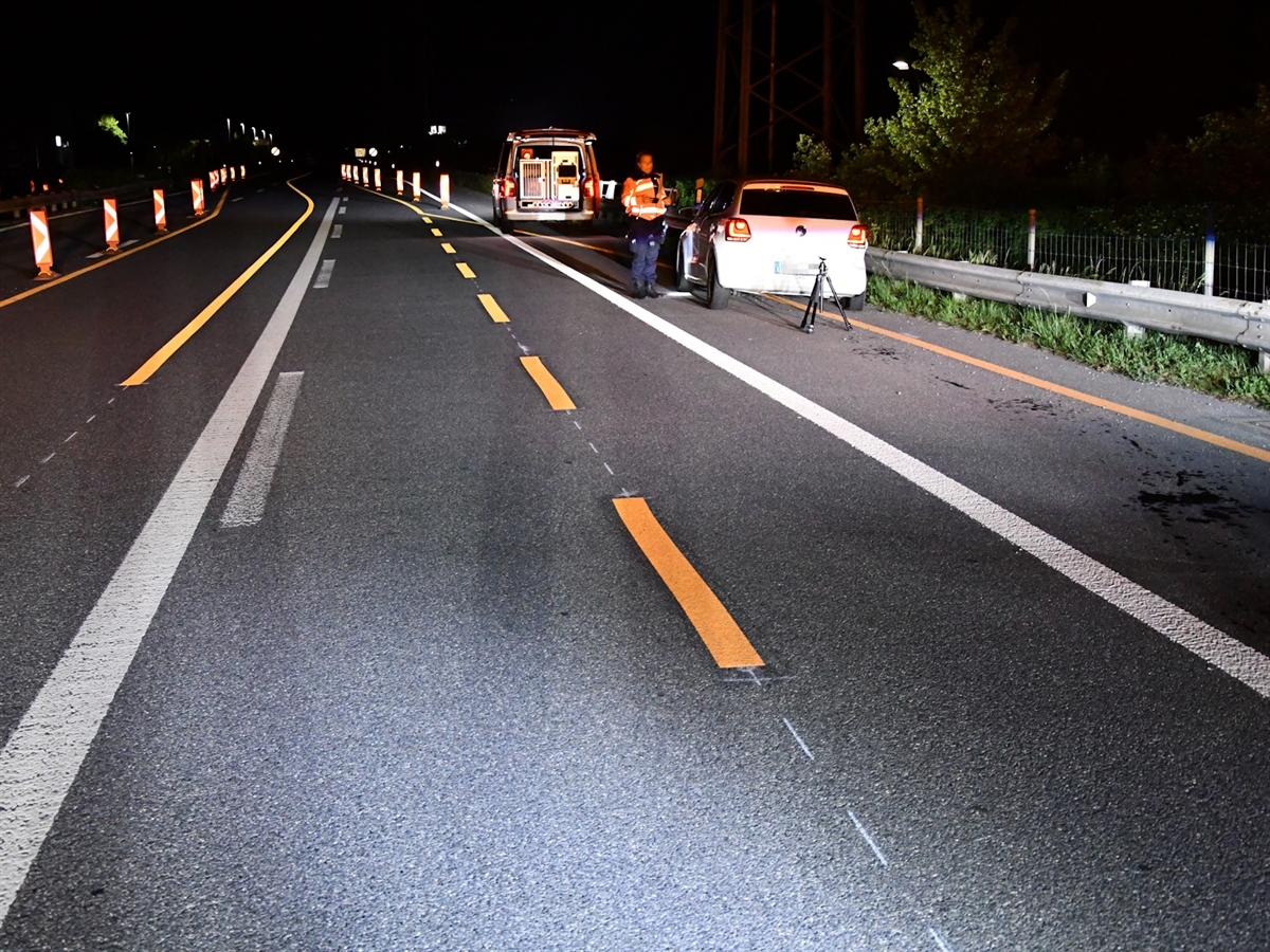 Nachtaufnahme auf der A13. Rechts das beschädigte Auto von hinten, nahe der Leitplanke.