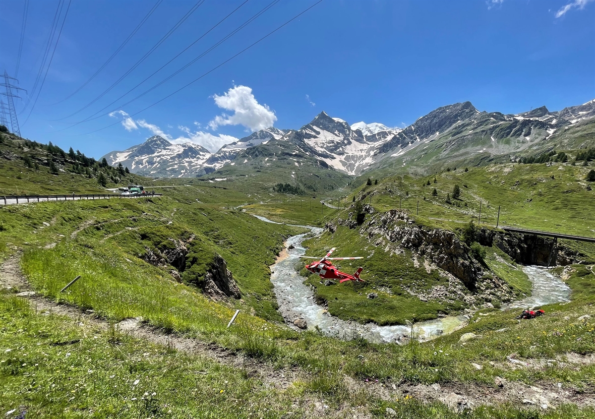 Rega Helikopter in der Luft über dem Bach, Motorrad im Hang