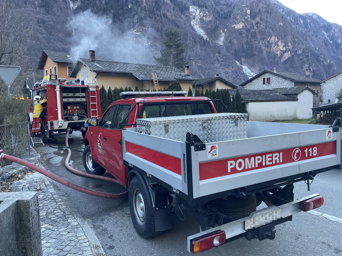 Feuerwehrautos vor dem Brandobjekt, bei welchem Rauch aus einem Fenster steigt.