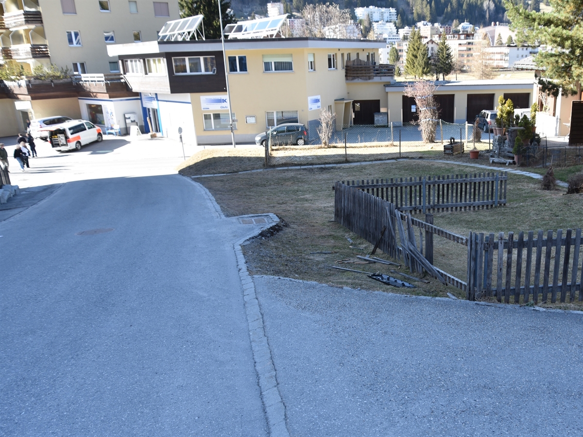 Die abfallende Quartierstrasse und der beschädigte Zaun. Weiter unten die Mattastrasse sowie ein Polizeiauto.
