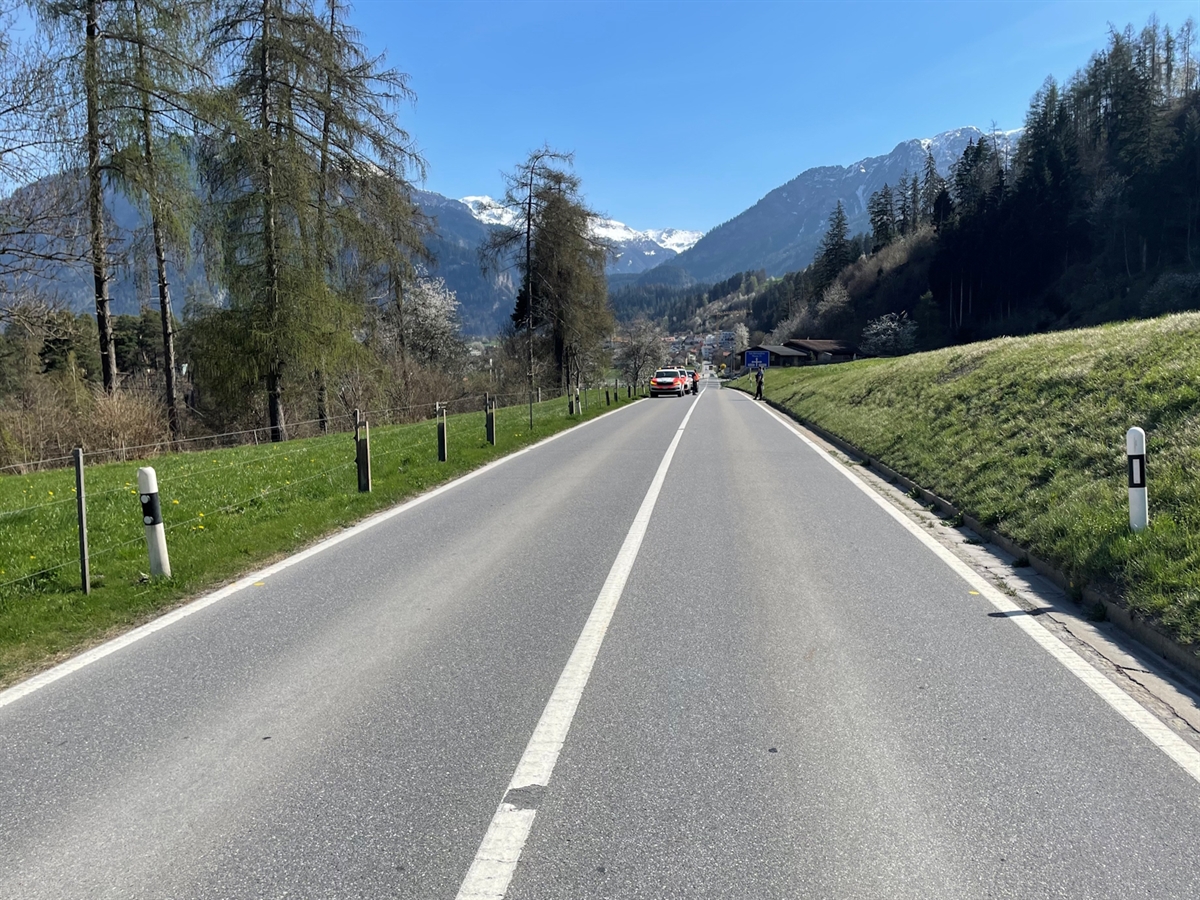 Übersichtsaufnahme in Richtung Thusis. Auf der Strasse stehen zwei Polizeiautos. Im Hintergrund Bergpanorama mit heiterem Himmel. 