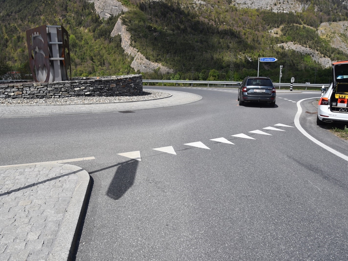 Rechts ein Polizeiauto ausserhalb der Fahrbahn. Links davon der Verkehrskreisel sowie das Unfallauto.