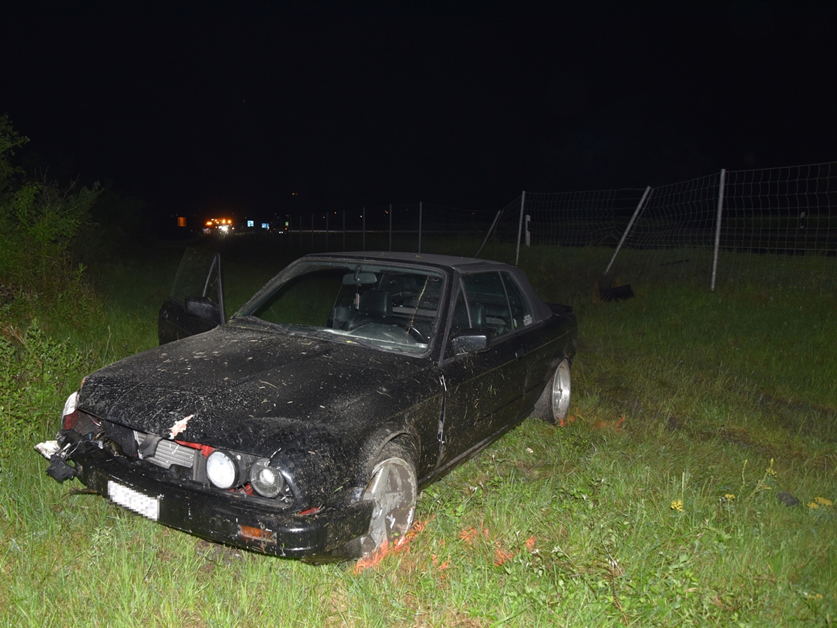 Das total beschädigte schwarze Auto neben der A13 im Wiesland