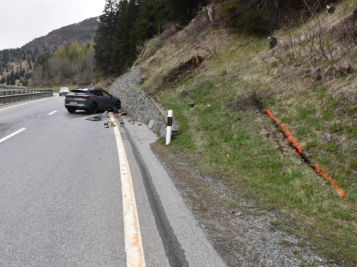 Das auf der Strasse stehende Auto. Daneben eine beschädigte Signalisation und von der Kollision mit der rechtsseitigen Böschung herunter gefallene Erde/Steine.