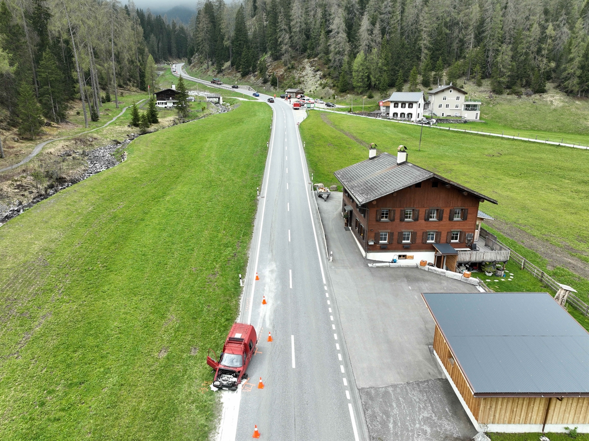 Strassenverlauf der Prättigauerstrasse bei der Unfallstelle in Davos Laret. Vorne links ist der rote beteiligte Personenwagen zu erkennen. Im Hintergrund sind die weiteren beiden beteiligten zwei Fahrzeuge zu erkennen. 