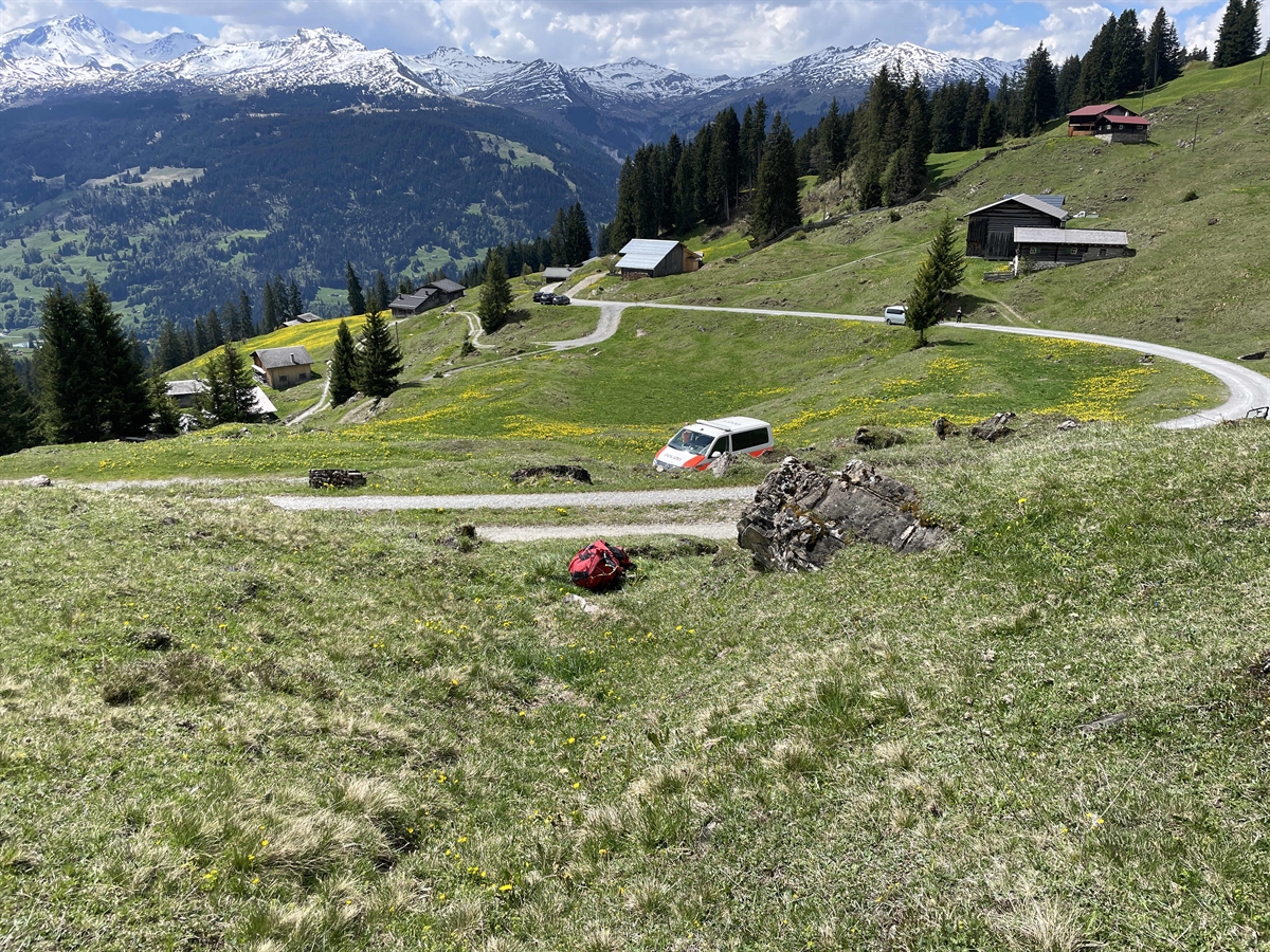 Landschaftsfoto mit der Örtlichkeit bei der Alp Bova, wo der Gleitschirmpilot abstürzte. Unterhalb der Alptrasse ist noch ein Patrouillenfahrzeug der Polizei zu erkennen.