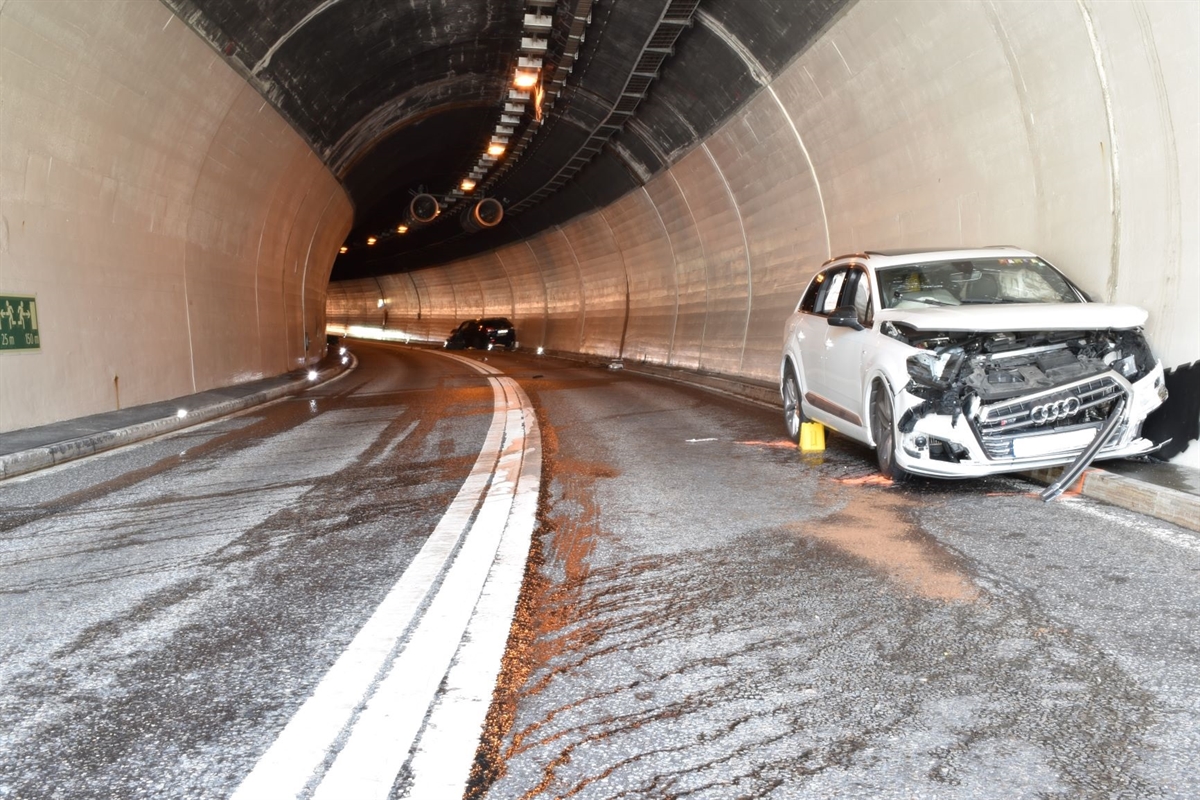 Tunnelinnenseite mit zwei stark beschädigten Fahrzeugen an der Tunnelwand der Bergspur