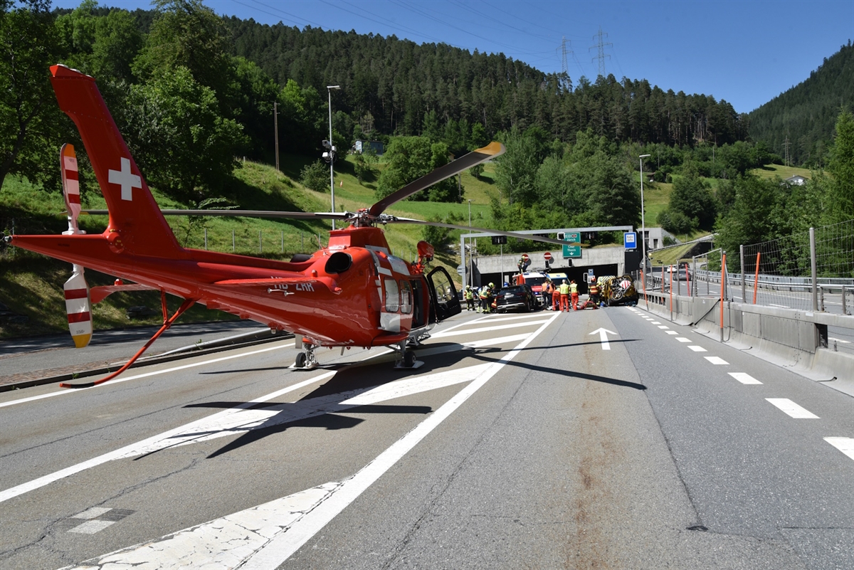 Die Unfallstelle mit einem Helikopter der Rega im Vordergrund. Im Hintergrund Einsatzkräfte die bei den total beschädigten Fahrzeugen die Personen betreuen.