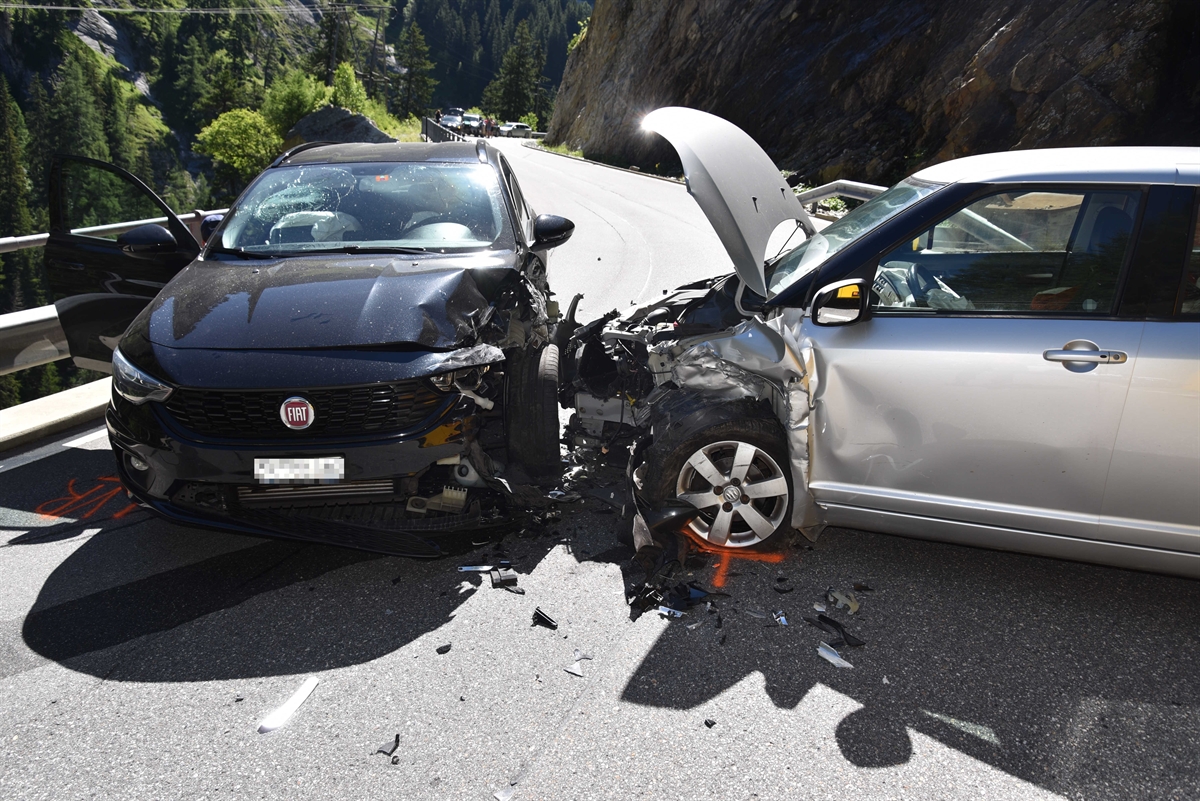 Endlage der beiden Fahrzeuge. Auf der Fahrbahn stehen linksseitig ein schwarzer Fiat und rechtsseitig ein silberner Suzuki. Beide Fahrzeuge haben eine komplett zerstörte Front und Seite. Beim silbernen Fahrzeug ist die Haube offen.