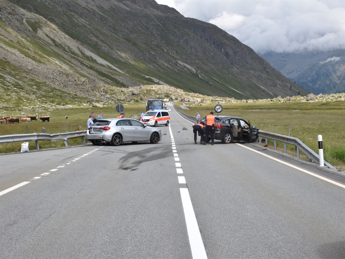 Eine lange Gerade mit Sicherheitslinie und Aufhebung des Überholverbots. Innerhalb dieses Verbots links das eine und rechts das andere total beschädigte Auto. Im Hintergrund Bergkulisse. 