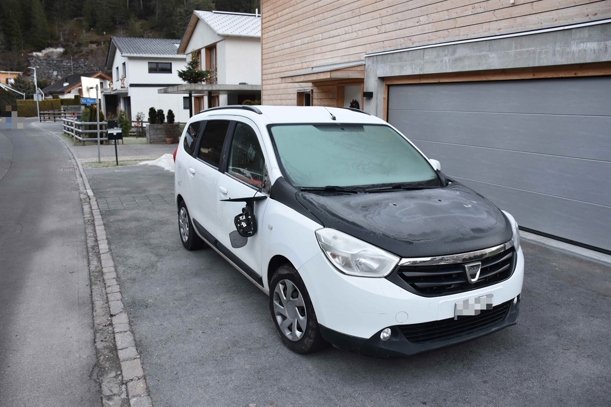 Personenwagen: Übersichtsaufnahme des weissen Personenwagens mit schwarzer Motorhaube. Das Fahrzeug steht vor dem Garagentor auf einem Parkplatz vor dem Einfamilienhaus. Der rechtsseitige Aussenrückspiegel wurde abgeschlagen und hängt nur noch am elektrischen Kabel.  