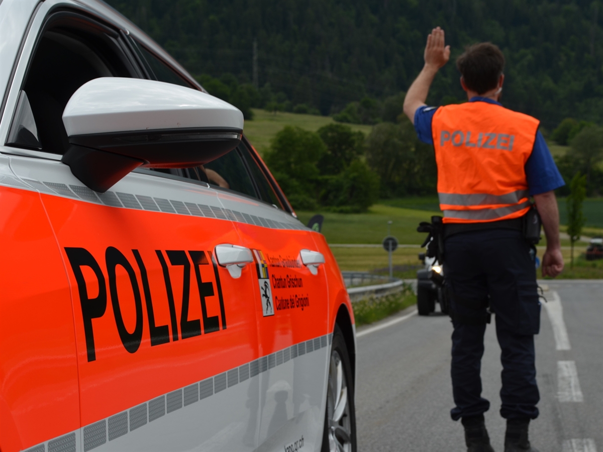 Symbolbild Polizeifahrzeug und Polizist mit Haltezeichen steht auf der Strasse