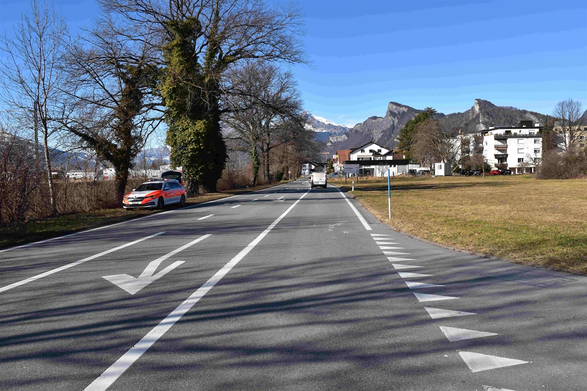 Übersichtsaufnahme der Luzisteigstrasse mit Einmündung der Falkinsstrasse in Richtung Bad Ragaz gesehen. Links neben der Strasse ist das Patrouillenfahrzeug abgestellt. Auf der Strasse unmittelbar der Einmündung wurden mit weisser Farbe Spuren vom Unfall eingezeichnet.