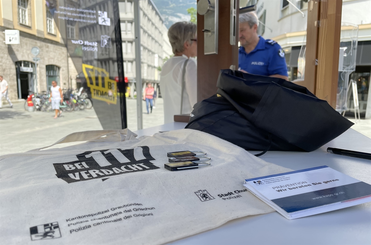 Give-Aways, im Hintergrund Polizist im Gespräch mit einer Frau