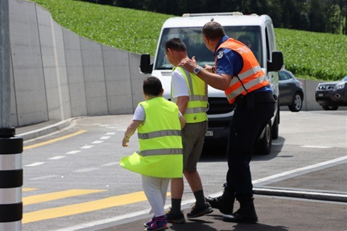 Polizist geht mit zwei Teilnehmenden über die Strasse