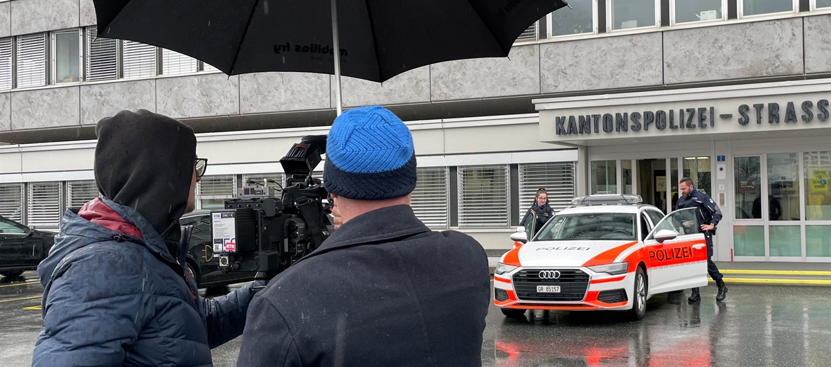 Patrouille steigt ins Polizeiauto, Journalisten unter dem Regenschirm