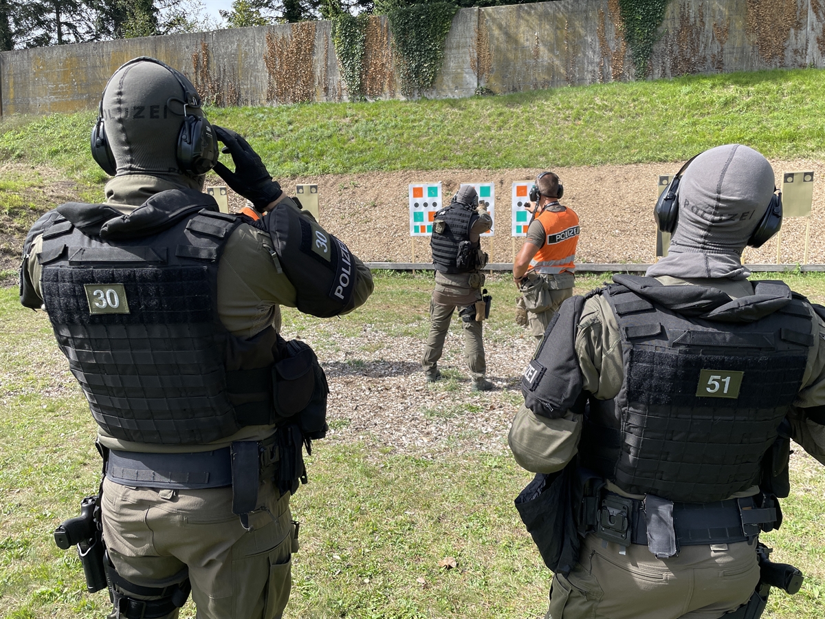 Interventionsleute von hinten, einer davon schiesst auf eine Zielscheibe