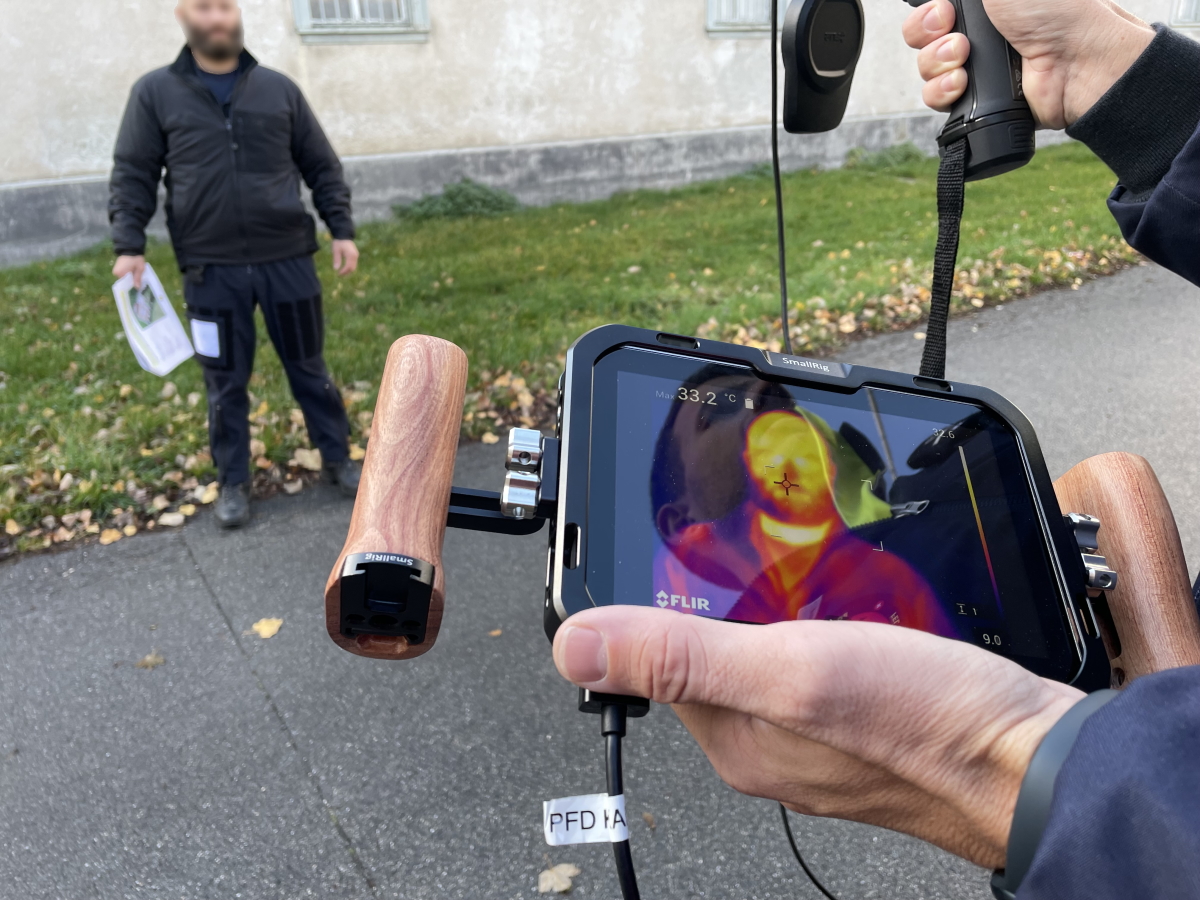 Ein Kursteilnehmer zielt mit der Hand-Wärmebildkamera auf einen seiner Kollegen und misst seine Temperatur am Kopf.