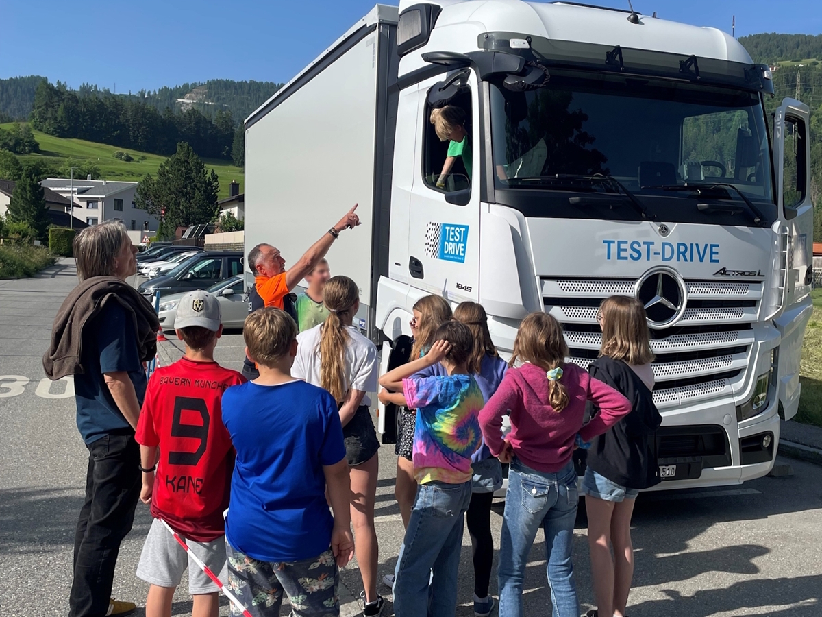 Der Verkehrsinstruktor erklärt den Kinder beim Seitenspiegel die verschiedenen Probleme des Toten Winkels