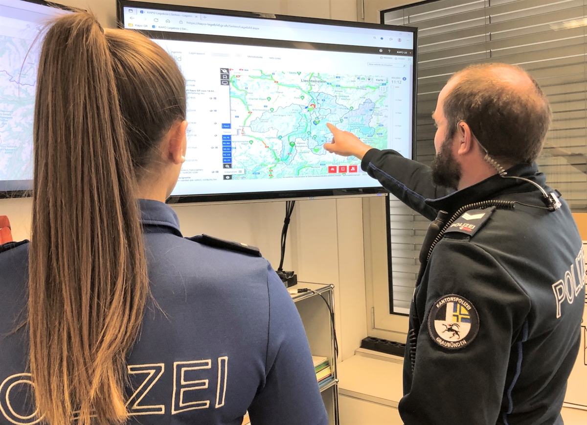 Polizistin und Polizist schauen Lagebild-Bildschirm an