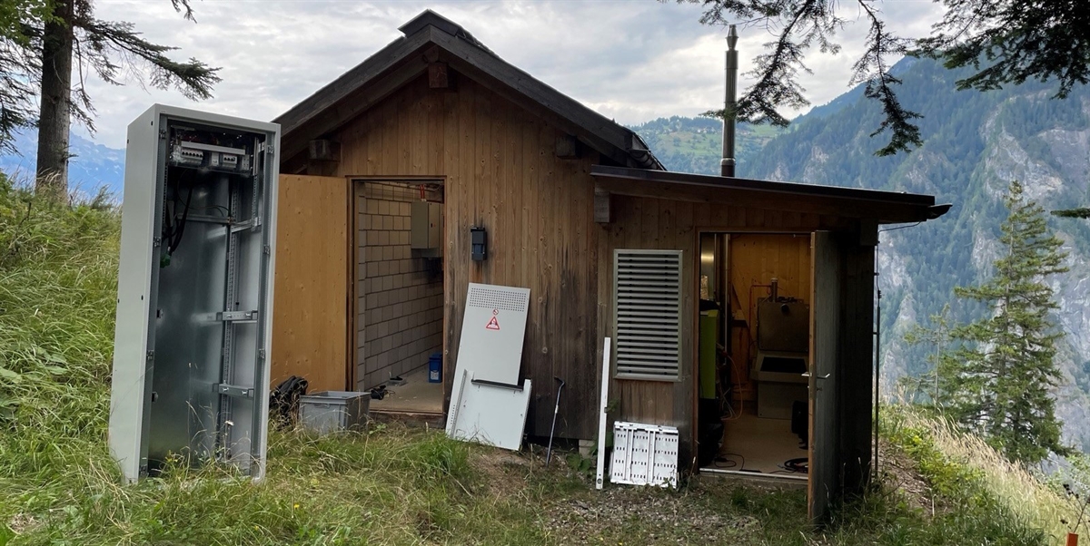 Häuschen der Basis- und Richtfunkstation in Rothenbrunnen mit Blick Tal auswärts. Vor dem Häuschen stehen leere Schaltkasten.